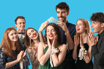 Young people crowning prom queen on blue background