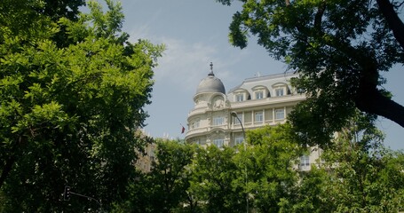Classic urban architecture, a white building with a flag rises above the trees
