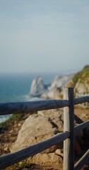 Sea washing the rocky shores and ledges. View from the top of the mountain from the observation deck through the fence, vertical video