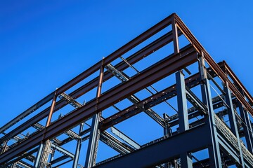The steel frame structure of the building is visible against the blue sky, showcasing industrial architecture and construction technology with steel beams for an exterior shot.