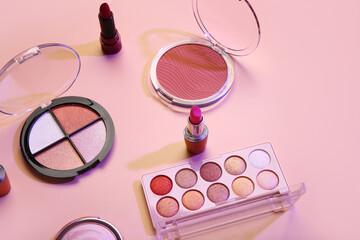 Beautiful palettes of eyeshadows and different decorative cosmetics on pink background
