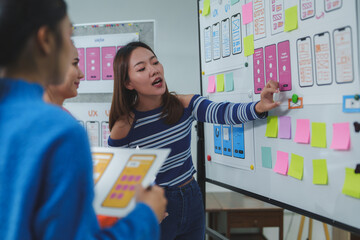 Ux designers are discussing user interface design using whiteboard and sticky notes in a modern office, collaborating on improving user experience and creating intuitive digital products