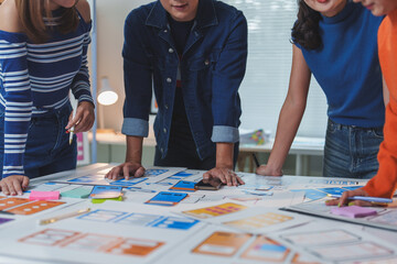 Four web designers are working together on a new mobile application, using sketches and wireframes...