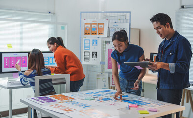 Web designers working together in the office analyzing mobile user interface designs displayed on a...