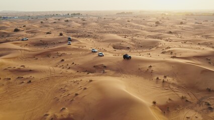 Cars driving off-road among sand dunes in the desert. Drone view