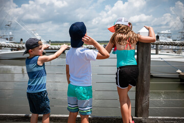 Kids on dock looking out at boats on summer vacation