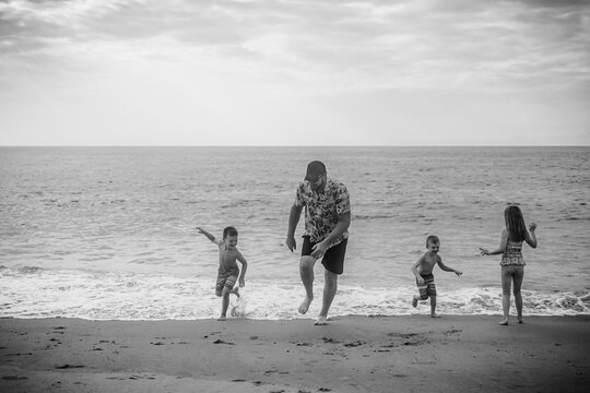 Dad and kids playing on beach during summer vacation
