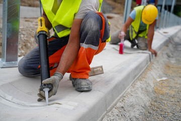 Filling gaps between concrete road curbs with silicon at highway construction site