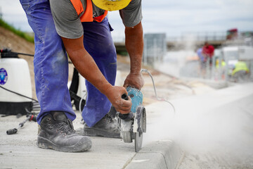 Cutting gaps between concrete road curbs with silicon to ensure long-lasting seal and prevent water damage at highway construction site