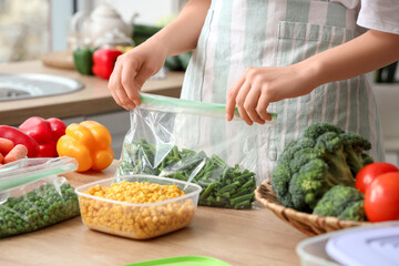Woman holding plastic bag with green beans for freezing in kitchen
