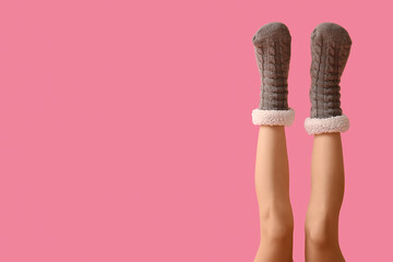 Legs of young woman in warm grey socks on pink background