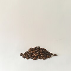 Obraz premium Small Pile of Coffee Beans: Roasted Coffee Beans Piled on a Light Surface, Emphasizing Natural Texture and Simple Composition.