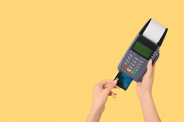 Woman with credit card and payment terminal on yellow background