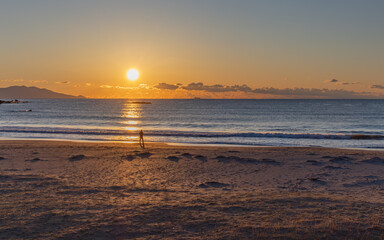 朝日に染まる波と砂浜
