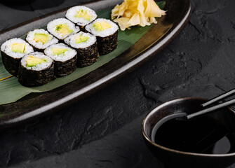 Avocado sushi roll with soy sauce on slate background