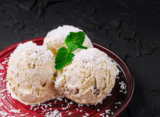 Ice cream dessert served on a red plate with coconut and mint