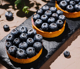 Blueberry tarts placed on a dark stone surface under natural light