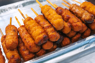 fried sausages in breadcrumbs on sticks at a street market in Asia. Korean hot dog or korndog. Asian fast food