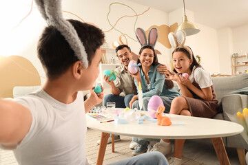 Happy family with painted eggs taking selfie at home on Easter Day