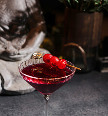 Cocktail served with garnished cherries in a dimly lit bar