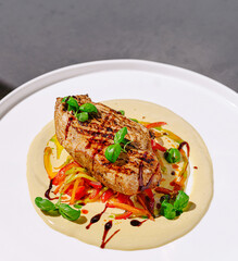 Grilled chicken breast served on creamy sauce with vegetables