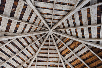 An artistic view of a wooden ceiling showcasing a beautifully intricate symmetrical design, highlighting craftsmanship and natural materials in architecture.