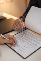 A man and a woman are signing a contract for a house. The man is holding a pen and the woman is...