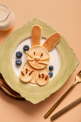 Funny Easter bunny pancakes with blueberry on orange background