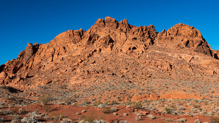 Fototapeta premium Majestic rocky peaks emerge from the ground showcasing the beautiful orange hues of nature, inviting exploration and adventure in a stunning desert landscape.