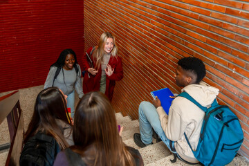 Obraz premium University students walking down the stairs greeting classmate