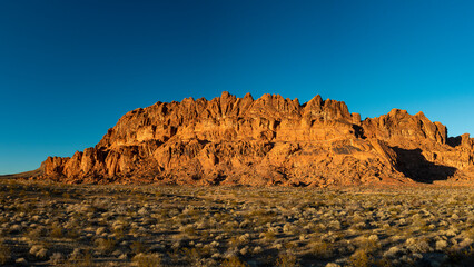 A breathtaking rock formation stands tall against a clear blue sky, representing the beauty of nature's sculpted landscapes in an arid environment.