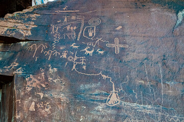 An ancient rock surface adorned with petroglyphs, depicting a rich history and cultural significance through intricate carvings and symbols.