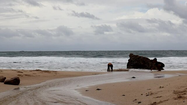 The crashing waves on the white sandy shore of Jumok Beach, Yogyakarta, at midday