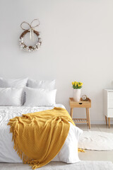 Interior of light bedroom with Easter wreath and tulips