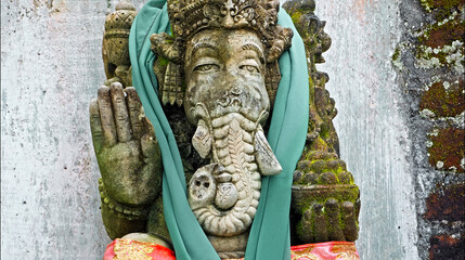 An old stone statue of Ganesha covered with moss.