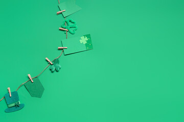 Paper garland with clover and leprechaun hat for St. Patrick's Day celebration on green background