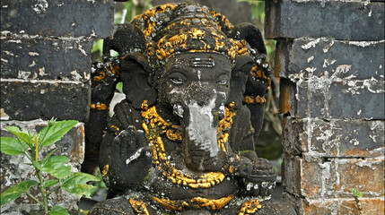 An old stone statue of Ganesha covered with moss.