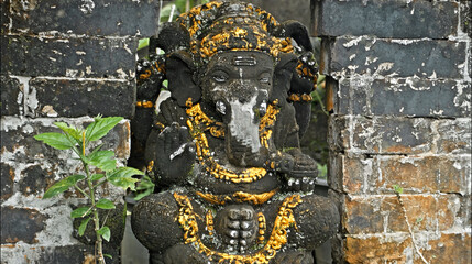 An old stone statue of Ganesha covered with moss.