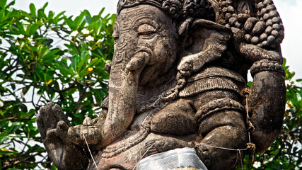 An old stone statue of Ganesha covered with moss.