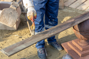 Man is painting a wooden board with a brush