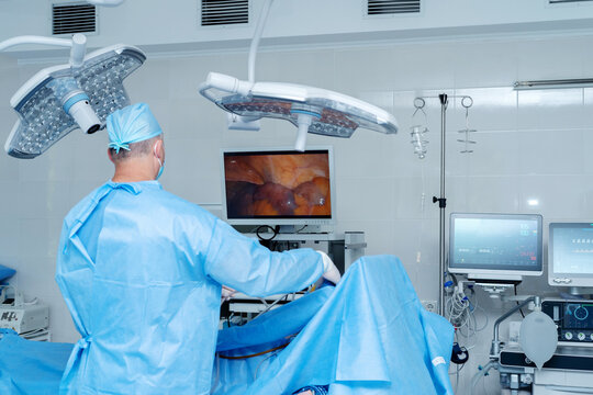 Laparoscopic cholecystectomy in the operating room, abdominal surgery, gallbladder removal. Surgeons in an operating room engage in a procedure, dressed in blue surgical gowns and caps.