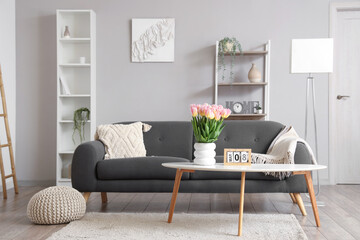 Interior of living room with sofa and tulips in vase for International Women's Day