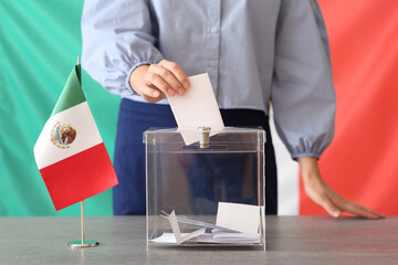 Voting young woman with Mexican flag near ballot box on table at polling station, closeup