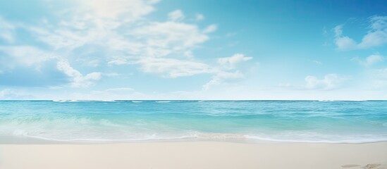 Fototapeta premium Tranquil tropical seascape featuring a clear blue sky and turquoise waters with gentle waves lapping against a soft sandy beach in the foreground