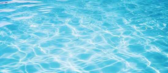 Crystal clear turquoise water rippling in a swimming pool, sunlight reflecting off the surface, creating shimmering patterns.