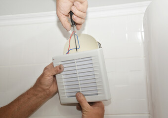 Replace and Install a bathroom exhaust fan. Repairman replace an exhaust fan in a bathroom
