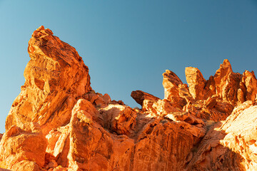Stunning orange rock formations rise sharply against a bright blue sky, showcasing nature’s...