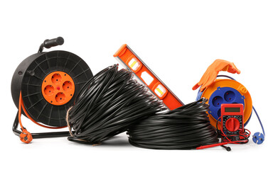 Rolled wires, extension cable reels, multimeter and spirit level on white background