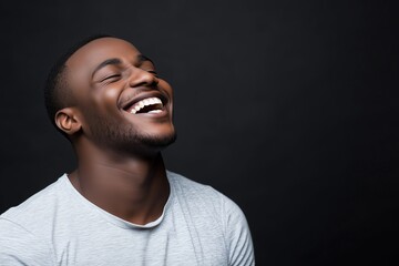 Obraz premium Young man laughing joyfully against black background. happiness and confidence
