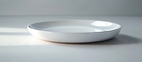 Minimalist white ceramic plate positioned at an angle on a light gray surface with soft shadows creating an elegant presentation background.